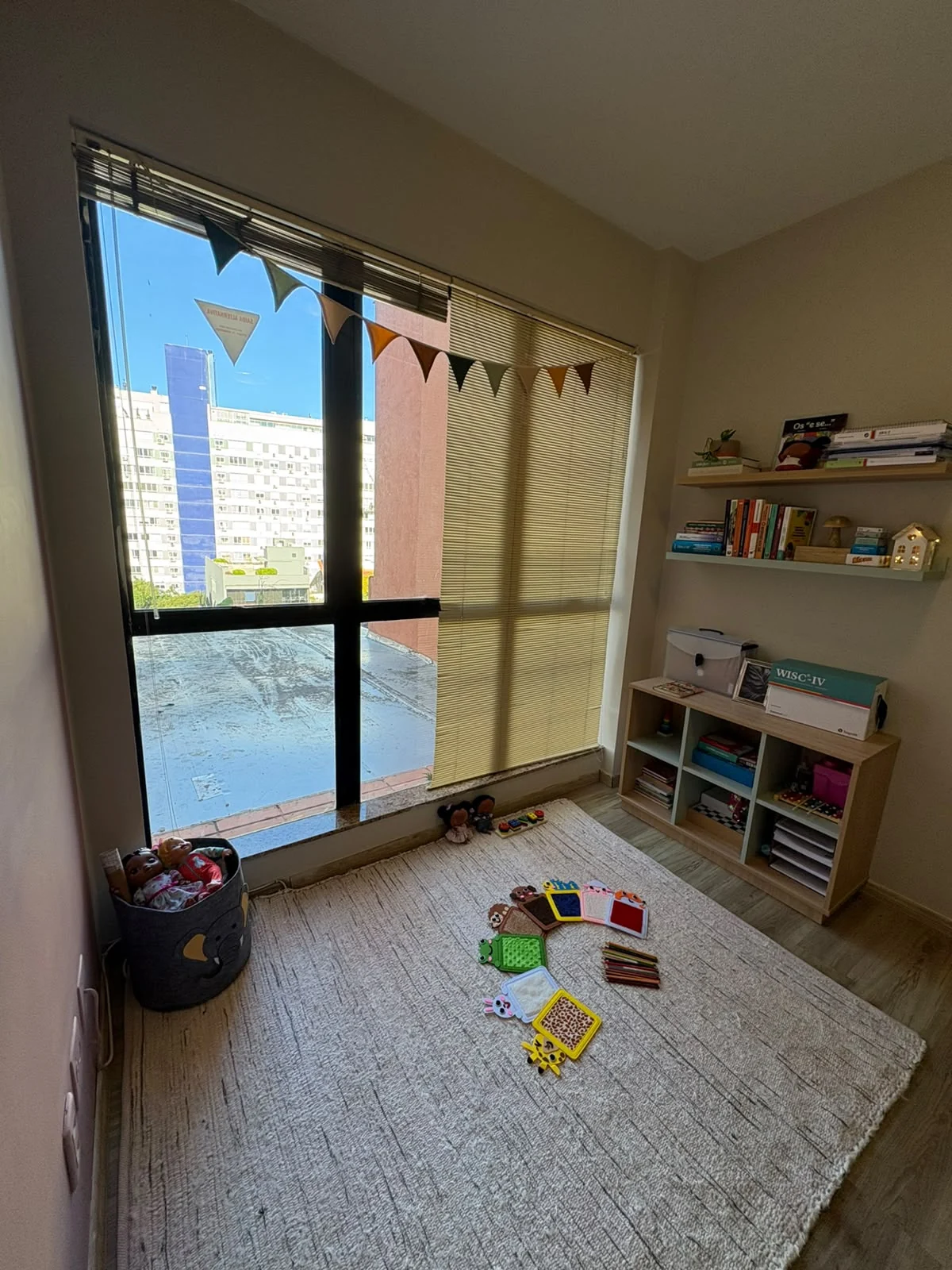 Espaço infantil do consultório com livros, brinquedos e janela